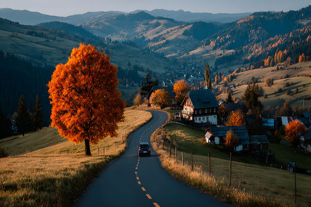 Winding road through picturesque countryside in autumn. a car travels along the path, flanked by vibrant orange trees and rustic houses, under a soft, sunset-lit sky with rolling hills in the background. Generative AIの素材