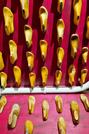 A striking display of vintage wooden shoe lasts arranged on a bold red wall. these bespoke, aged...