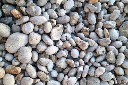 A collection of smooth, rounded gray pebbles tightly packed together, showcasing natural stone...