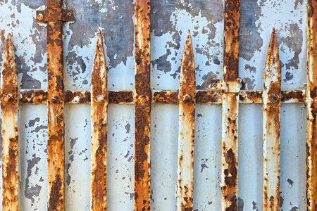Weathered metal gate featuring rusted vertical bars and peeling paint. ideal for industrial-themed...