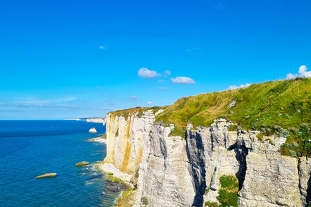 Majestic coastal cliffs rise dramatically against a backdrop of clear blue skies. verdant grass tops...