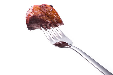 Fried piece of meat on a fork isolated on white backgroundの写真素材