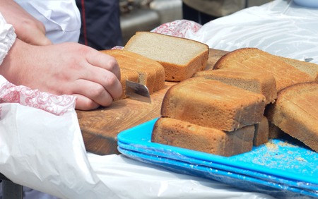 Male hands cutting russian traditional rye bread on the wooden board