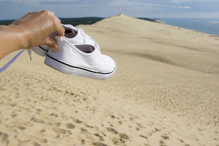 White travelers sneakers on the background of Pilat dune, the largest sand dune in Europeの写真素材