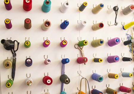 Multicolored coils and scissors on the wall. Workplace seamstressesの写真素材