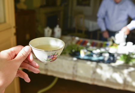 A female hand holds a French porcelain mug with green teaの写真素材