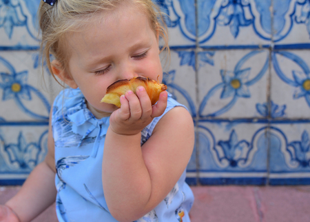 The girl is eating Pasteis de Belem egg tart. Azulejos tile on a backgroundの写真素材