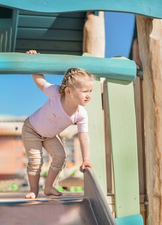 Girl of 3 years old sliding outdoor on a playgroundの写真素材