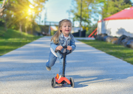 Little girl is riding a scooter in the parkの写真素材