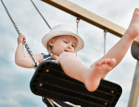 Girl 3 years old riding on a swingの写真素材