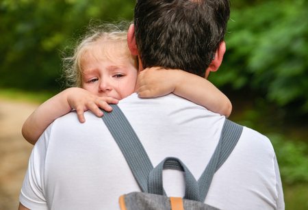 A little girl cries and hugs fatherの写真素材