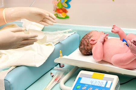 A nurse weighs on the scales of a newborn baby