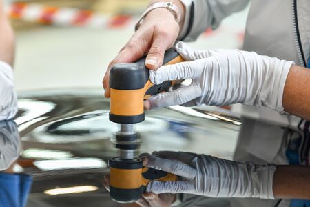 Operator holds a polisher in the hand for scratch on a carの写真素材