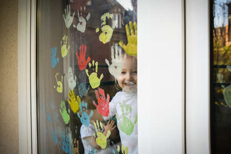 Children paint with palms on the window. Quarantine Stay at home