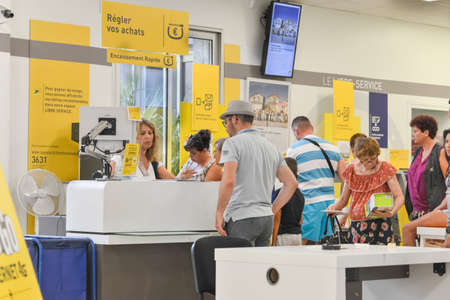 CAP D'AGDE, FRANCE - JULY 27, 2016: People stand in a queue for post office services. Sending...