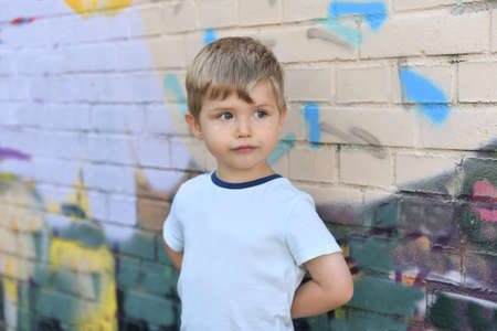 Boy with blue eyes near a colorful wallの写真素材