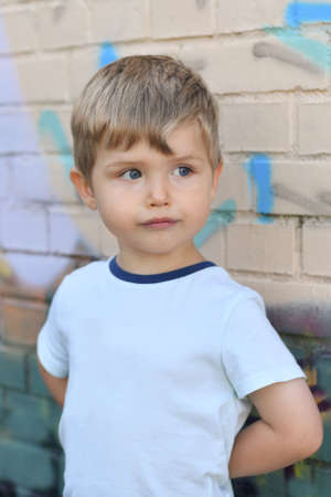 A boy with blue eyes near a colorful wall