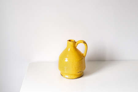 Yellow vase on a table on a white backgroundの写真素材