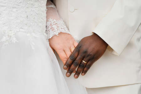 African and Causian couple holding hands with ring