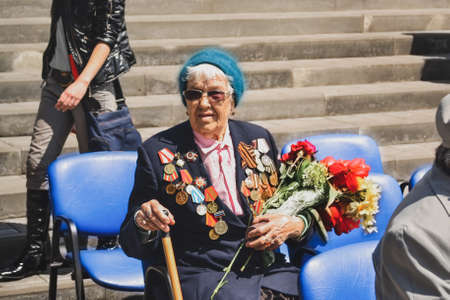 PYATIGORSK, RUSSIA - MAY 09, 2011: War veteran woman with flowers on the Victory Day celebration. Russian babushkaのeditorial素材
