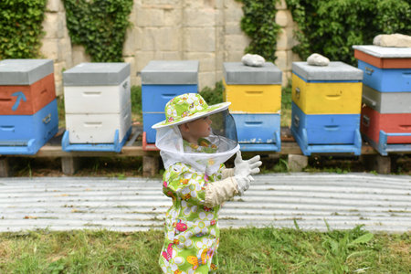 A beekeeper child in apiary in a protective suit