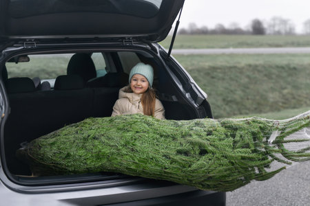 A girl sitting in the trunk with a Christmas treeの写真素材