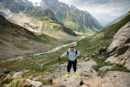 A woman with backpack and sticks in the Caucasus mountains