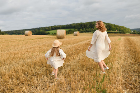 Mother plays with daughter in a field with wheatの写真素材