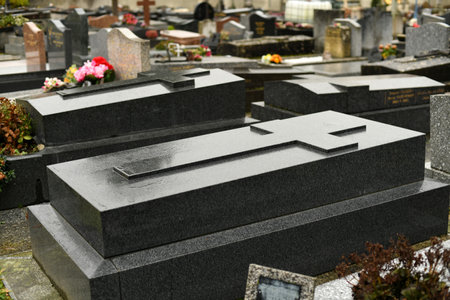 Cross on a black marble slab on a grave in a cemetery