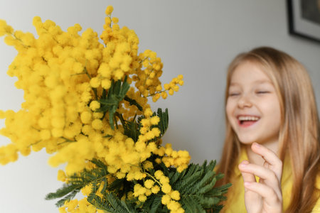 A girl smelling yellow mimosa at springの写真素材