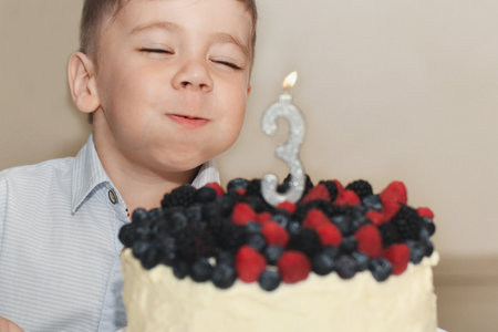Boy blows out the candles for his birthdayの写真素材