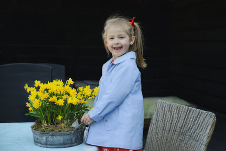A girl in a dress near a pot of daffodilsの写真素材