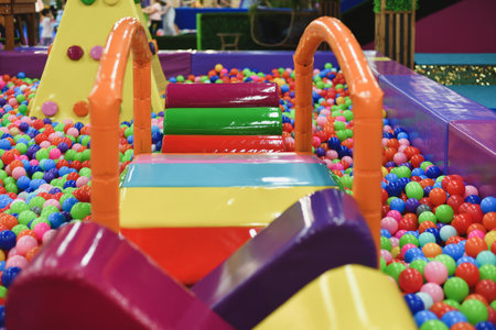 A dry paddling pool in playing centre with plastic balls.