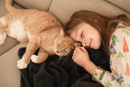 A girl near a ginger cat on the sofaの写真素材