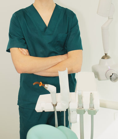 Dentist man in office near chair with dental toolsの写真素材