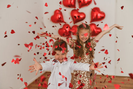 Children enjoy heart-shaped confetti. Balloons are in the background.Valentines Day conceptの写真素材