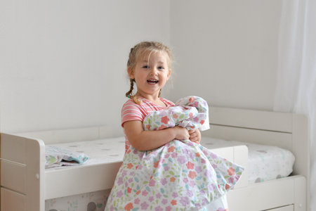 A girl makes a bed in the children roomの写真素材