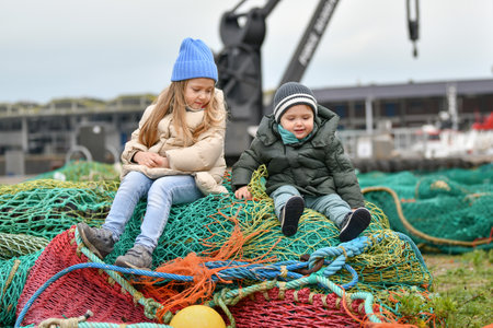 Brother and sister playing at the fishing netsの写真素材