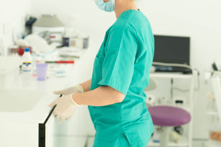 Dental assistant in glove and mask and uniform cleaning dental officeの写真素材