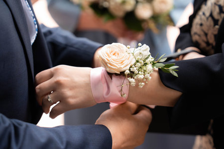 The bridesmaid gets a bracelet made of a pink ribbon and roses tied on her handの写真素材