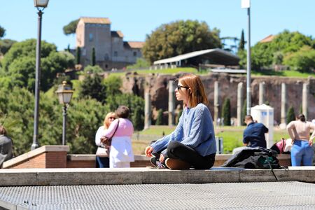 The girl is sitting in the Lotus position listening to music and Smoking a cigarette. Italy, Rome, may 2019のeditorial素材