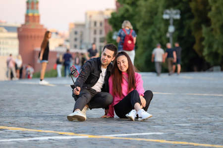 A guy and a girl are making a selfie on a street, Red Square, summer day. Russia Moscow June 2020.のeditorial素材