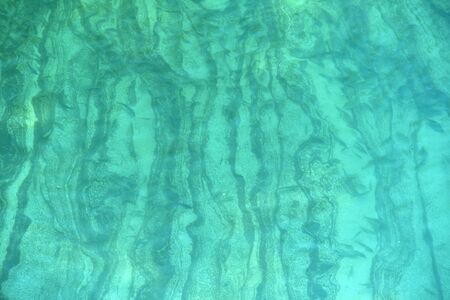 On a sunny day, the bottom of a mountain river is clearly visible.