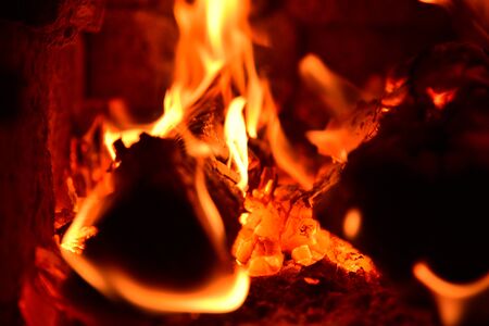Tongues of tortuous flame rise above the burning wood, turning them into red coals.の写真素材