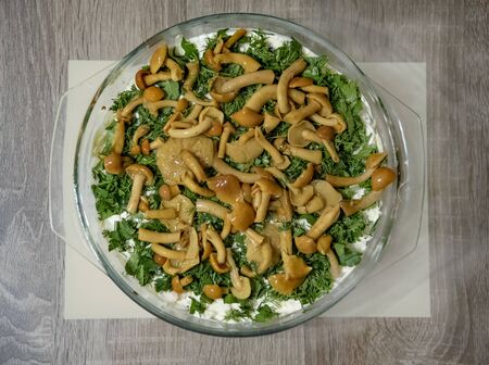 On the table is a glass plate in which a vegetable salad with mayonnaise and mushrooms is on top.の写真素材