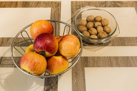 On a table there is a vase of apples and walnuts are lying nearby.の写真素材