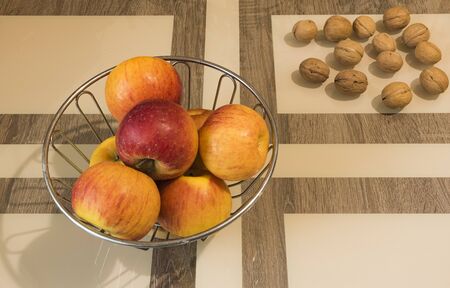 On a table there is a vase of apples and walnuts are lying nearby.の写真素材