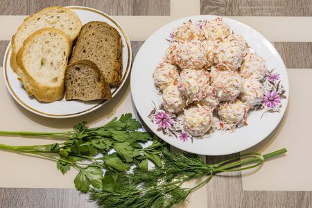 Rafaello cold appetizer of olives, cheese, crab meat, eggs, mayonnaise next to a plate with bread and fresh dill with parsley.の写真素材