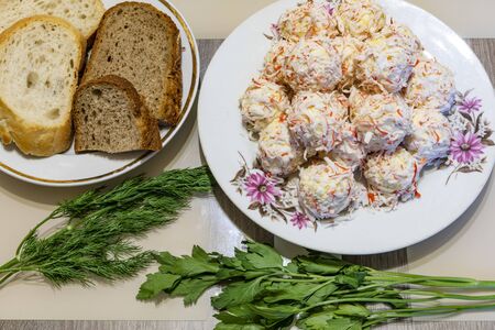 Rafaello cold appetizer of olives, cheese, crab meat, eggs, mayonnaise next to a plate with bread and fresh dill with parsley.の写真素材