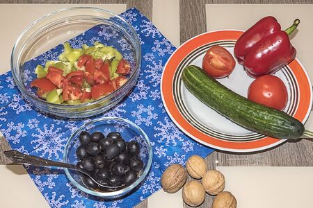 A variety of ingredients for the preparation of vegetable salad with cheese lie on the table.の写真素材